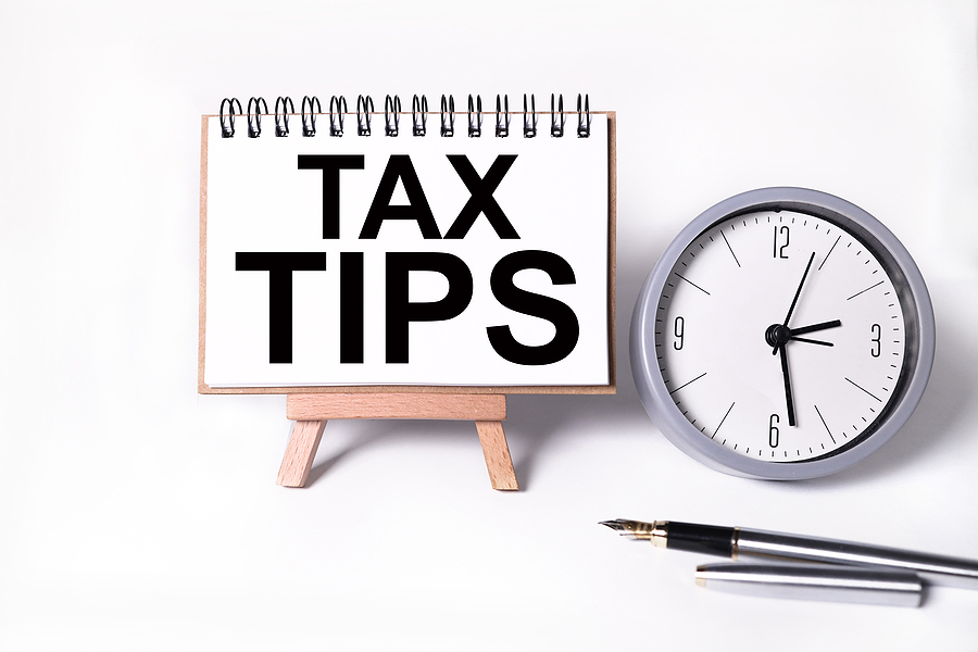TAX TIPS. text on white notepad paper on white background. near the table clock